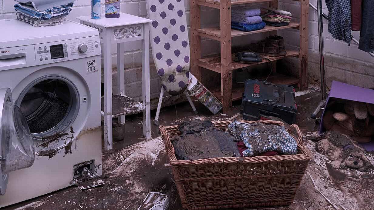 Schade aan de wasruimte Wasruimte met een vuile wasmand en een wasmachine.